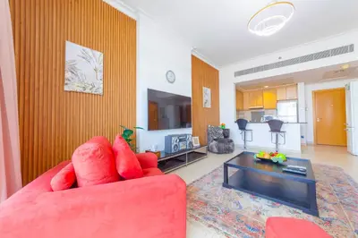 a living room with a red couch and a table at An Elegant Fully Furnished 1 Bedroom Apartment in Clayton Residency, Business Bay, Dubai in Dubai