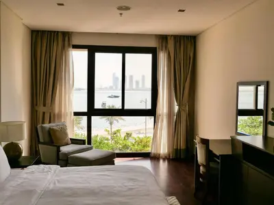 a hotel room with a bed and a chair and a window at Waterfront 2BR Apartment with Sea Views in Dubai