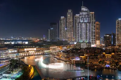 a city skyline at night with a river and buildings at Grande Signature Residence, Burj Khalifa and Fountain View in Dubai