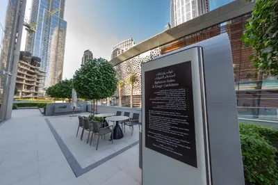 a sign with chairs and a table in a city at Grande Signature Residence, Burj Khalifa and Fountain View in Dubai