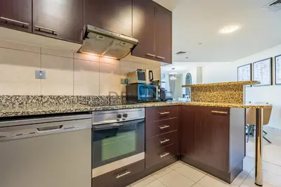 a kitchen with brown cabinets and a stove top oven at Elegant 2BR in Sky Gardens DIFC by Deluxe Holiday Homes in Dubai