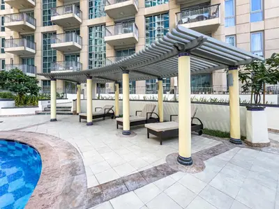 a pavilion with benches and a pool in front of a building at Kensington Chic 1BR Fountain-view Flat Downtown Burj Khalifa in Dubai