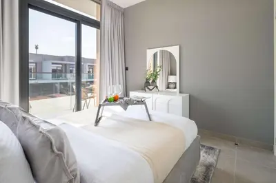 a bedroom with a bed and a large window at Frank Porter - Ranches 3 in Dubai