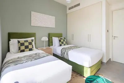 two beds in a small room with white and green at Frank Porter - Ranches 3 in Dubai