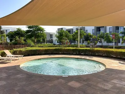 a swimming pool with an umbrella in a courtyard at Frank Porter - Ranches 3 in Dubai