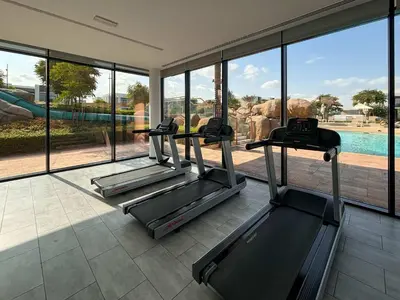 a gym with two treadmills in a room with a view of a pool at Frank Porter - Ranches 3 in Dubai