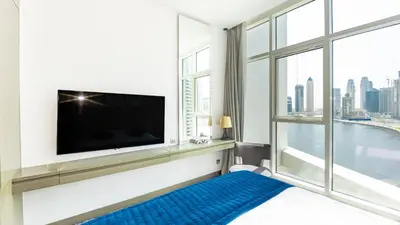 a living room with a large window and a flat screen tv at Conveniently Located Apartment With Waterfront View in Dubai