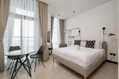 a white bedroom with a bed and a table and chairs at Studio Revved Up in 15 Northside with Pool and Gym in Dubai