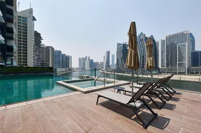 a pool with two chairs and umbrellas on a building at Studio Revved Up in 15 Northside with Pool and Gym in Dubai