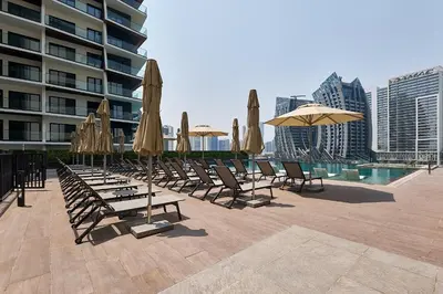 a row of chairs and umbrellas next to a pool at Studio Revved Up in 15 Northside with Pool and Gym in Dubai