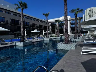 a pool with chairs and palm trees in a hotel at Oakley Square Oasis in JVC in Dubai