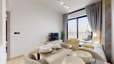 a dining room with a table and chairs and a large window at Locations I Binghatti Luna - JVC I Modern 1BR Apartment I Upgraded Interiors & Comfortable Stay I Scenic Community & Skyline Views in Dubai