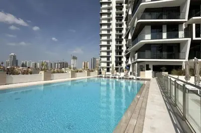 a large swimming pool in front of a building at Locations I Binghatti Luna - JVC I Modern 1BR Apartment I Upgraded Interiors & Comfortable Stay I Scenic Community & Skyline Views in Dubai