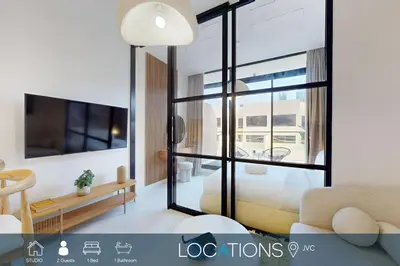 a living room with a couch and a large window at Loci Residences - Vibrant Studio in JVC in Dubai