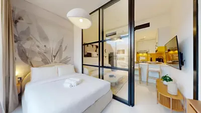 a bedroom with a white bed and a bathroom at Loci Residences - Vibrant Studio in JVC in Dubai