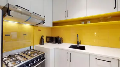 a kitchen with white cabinets and a stove and a sink at Loci Residences - Vibrant Studio in JVC in Dubai