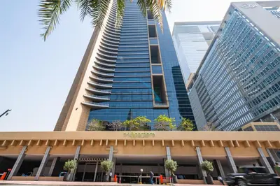 a tall building with a palm tree in front of it at Delightful 2BR at Sky Gardens DIFC by Deluxe Holiday Homes in Dubai