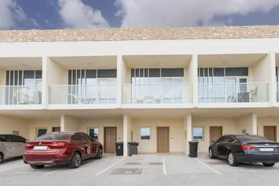 two cars parked in a parking lot in front of a building at Family Friendly, 2BR Townhouse in Rukan Community, Dubai Land - Allsopp & Allsopp in Dubai