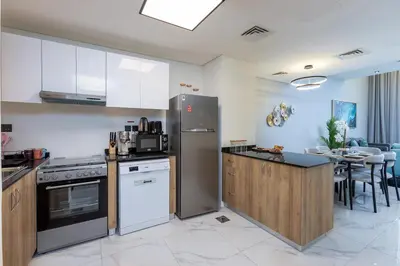 a kitchen with white appliances and a dining room at Family Friendly, 2BR Townhouse in Rukan Community, Dubai Land - Allsopp & Allsopp in Dubai