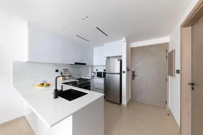 a kitchen with white counters and a refrigerator at Bright 1BR with balcony in Binghatti Corner in Dubai