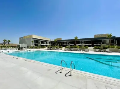 a large swimming pool with chairs and a building at Bright 1BR with balcony in Binghatti Corner in Dubai