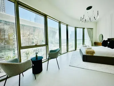 a bedroom with a bed and chairs and a large window at Venduras Homes -Grande Tower, Downtown Dubai, Burj Khalifa & Fountain Views in Dubai