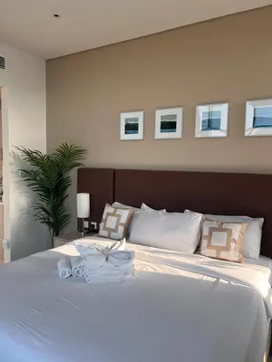 a bedroom with a large white bed with pictures on the wall at Suite in Seven Palm Corner Unit Rooftop Floor in Dubai