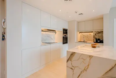 a kitchen with white cabinets and a marble counter at Breathtaking 1BDR Apartment in Dubai Marina I Bonair I Park Islands in Dubai