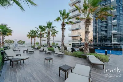 a patio with tables and chairs and palm trees at Luxury Studio in DAMAC Hills with Premium Amenities in Dubai
