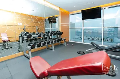 a room with a gym with a bench and weights at Luxury Studio in DAMAC Hills with Premium Amenities in Dubai