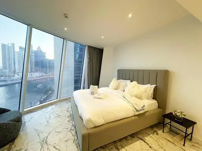 a bedroom with a bed and a large window at Modern & Bright Canal View 2BR Near Dubai Mall by Vibel in Dubai