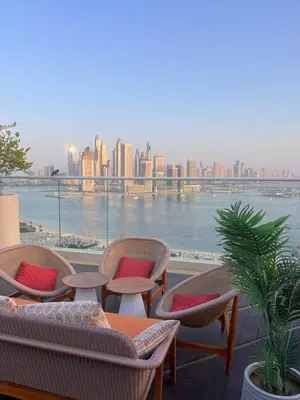 a balcony with chairs and tables and a view of the city at Charming Studio in Seven Palm with Balcony Rooftop Floor in Dubai