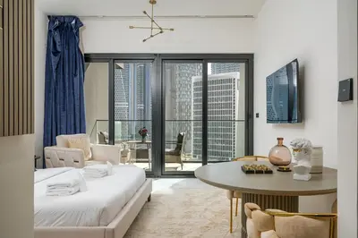 a living room with a bed and a table and a room with a view at Business Bay Studio Binghatti Canal with Terrace in Dubai