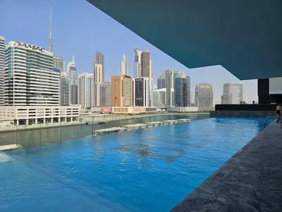 a large swimming pool with a city in the background at Business Bay Studio Binghatti Canal with Terrace in Dubai