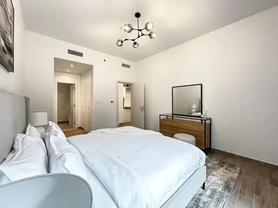 a white bedroom with a large bed and a mirror at Super Spacious 2BR with Designer Touch in Dubai