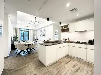 a kitchen and dining room with white cabinets and a table at Super Spacious 2BR with Designer Touch in Dubai