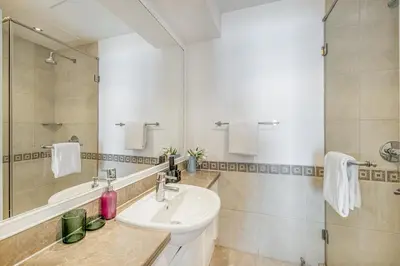 a white bathroom with a sink and a shower at Daniels 2BR at Fairmont South The Palm Jumeirah in Dubai