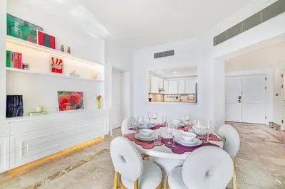 a white dining room with a table and chairs at Daniels 2BR at Fairmont South The Palm Jumeirah in Dubai