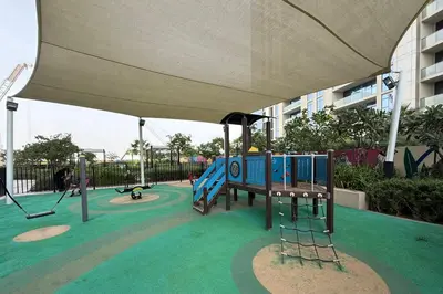 a playground with a swing set and an umbrella at Cozy 2BR in Business Bay, Aykon Tower in Dubai