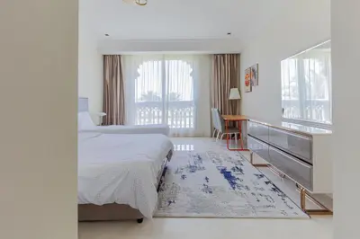 a bedroom with a bed and a desk and a window at Spacious New 2 BDR, Pool and Beach Access in Dubai