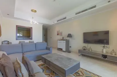 a living room with a blue couch and a flat screen tv at Spacious New 2 BDR, Pool and Beach Access in Dubai