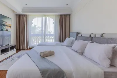 a large white bed in a room with a large window at Spacious New 2 BDR, Pool and Beach Access in Dubai