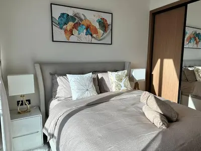a bedroom with a bed and a night stand with a lamp at Gorgeous 1br Apt In Jvc in Dubai