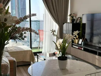 a living room with a table and a large window at Gorgeous 1br Apt In Jvc in Dubai