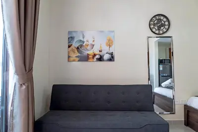 a couch in a room with a mirror and a clock at Studio in Dubai Pool, Gym & Stunning Views in Dubai