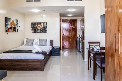 a bedroom with a bed and a table and a kitchen at Studio in Dubai Pool, Gym & Stunning Views in Dubai