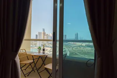 a balcony with a table and chairs and a view of a city at Studio in Dubai Pool, Gym & Stunning Views in Dubai