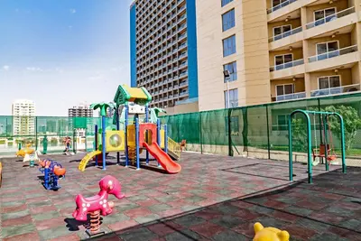 a playground with play equipment in front of a building at Studio in Dubai Pool, Gym & Stunning Views in Dubai
