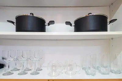 two pots and glasses on a shelf with glasses at Luxury JLT Studio Lake View Metro & Marina in Dubai