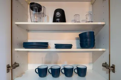 a shelf with blue cups and plates on it at Luxury JLT Studio Lake View Metro & Marina in Dubai